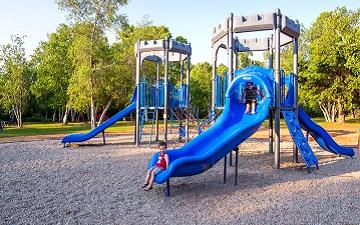 Children playing on a blue castle-themed playground structure with slides.